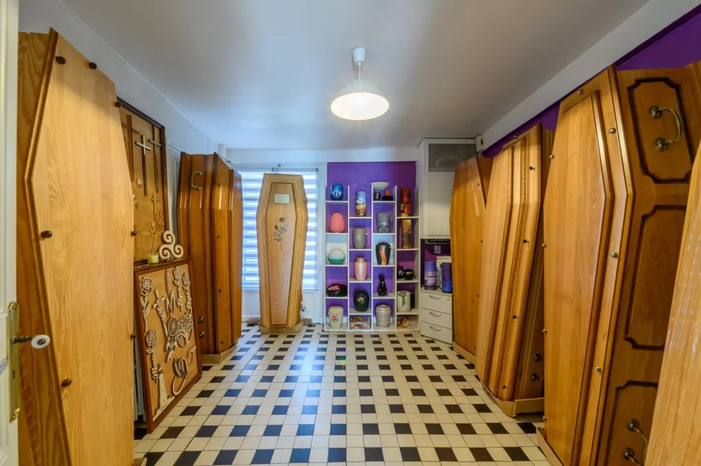 Salle d'exposition de la marbrerie présentant divers cercueils et urnes funéraires.